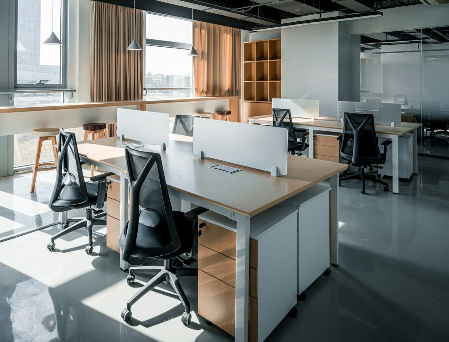 Pencere kenarında yan yana masaları olan aydınlık bir ofis